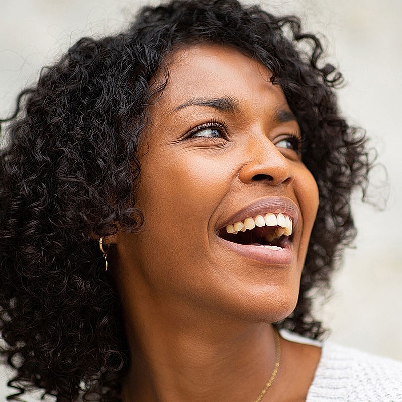 Smiling woman with curly hair looking upwards.
