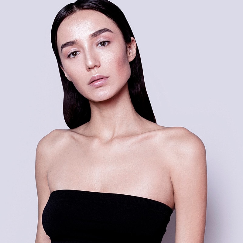 Model with long dark hair and natural makeup.
