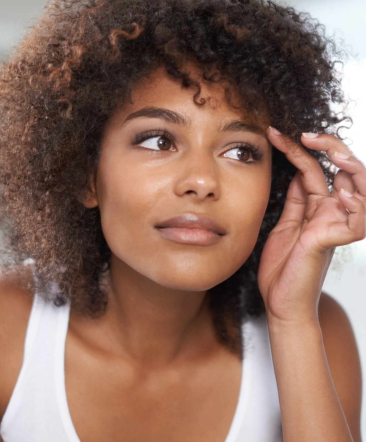 Young woman with curly hair deep in thought.