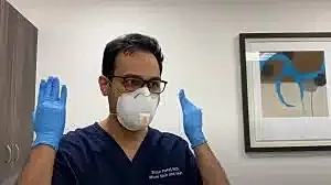 Healthcare professional adjusting mask and gloves.