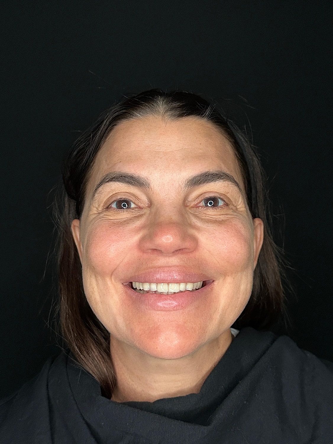 Smiling woman with dark background.