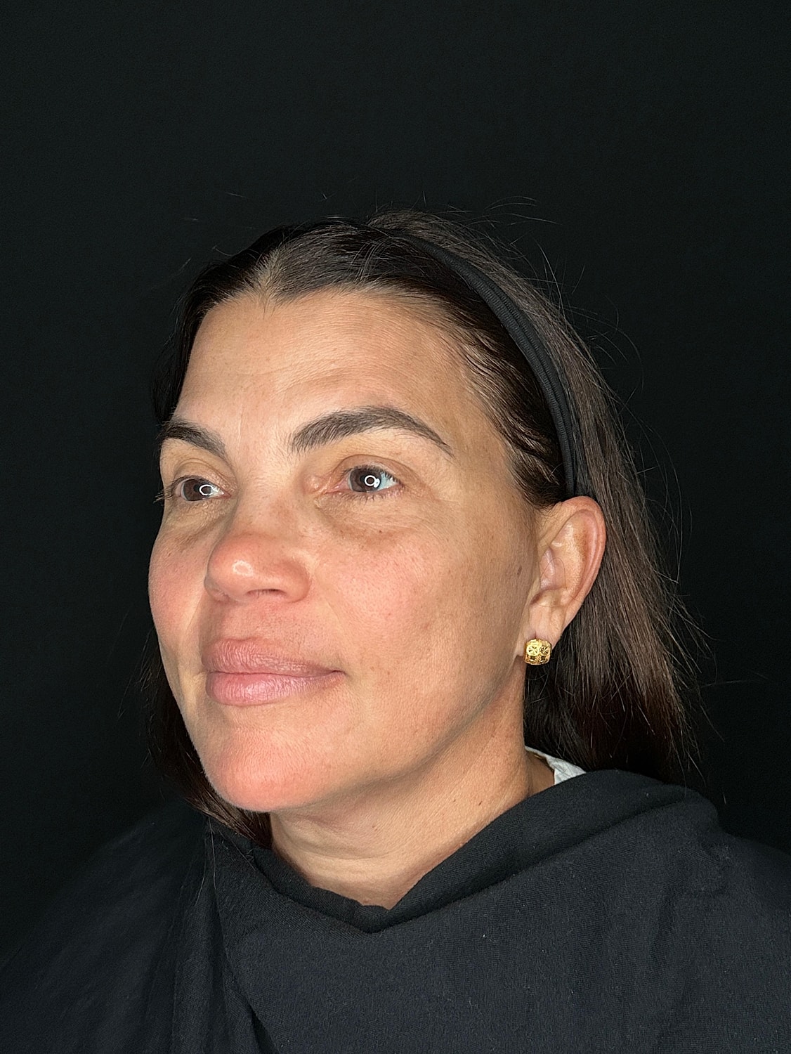 Woman with natural makeup against black background.