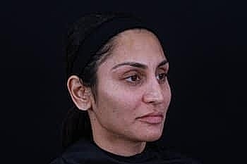 Woman with simple makeup against a dark background.