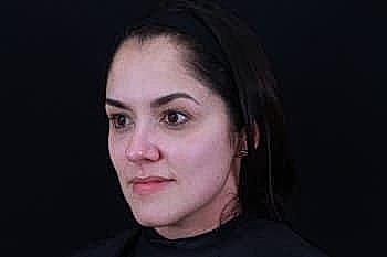 Woman with natural makeup against a dark background.
