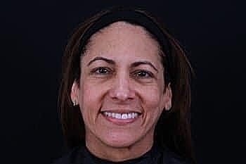 Smiling woman with long hair on dark background.