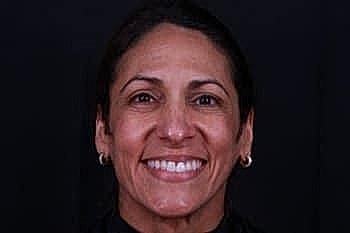 Smiling woman against a dark background.