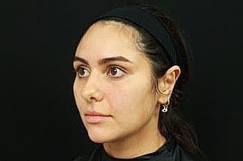 Young woman with dark hair against black background.