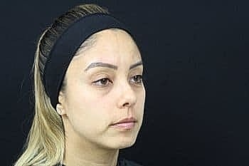 Woman with a headband against a dark background.