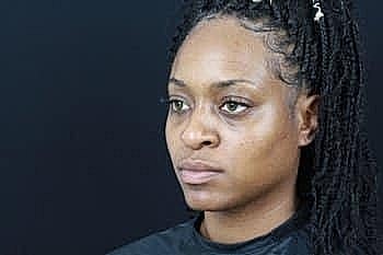 Woman with braided hair against a dark background.