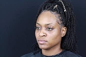 Woman with braided hair against dark background.