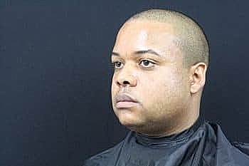 Man with short hair against black background.