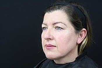 Woman with natural makeup against black background.