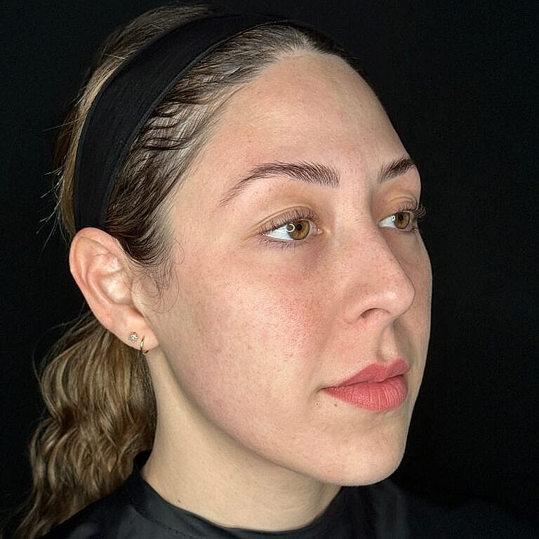 Woman with natural makeup, profile view against black background.