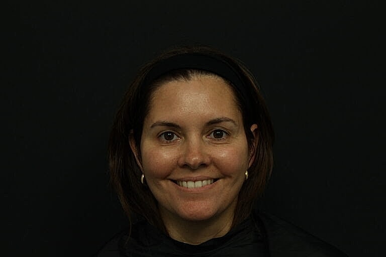 Woman smiling in front of a dark background.