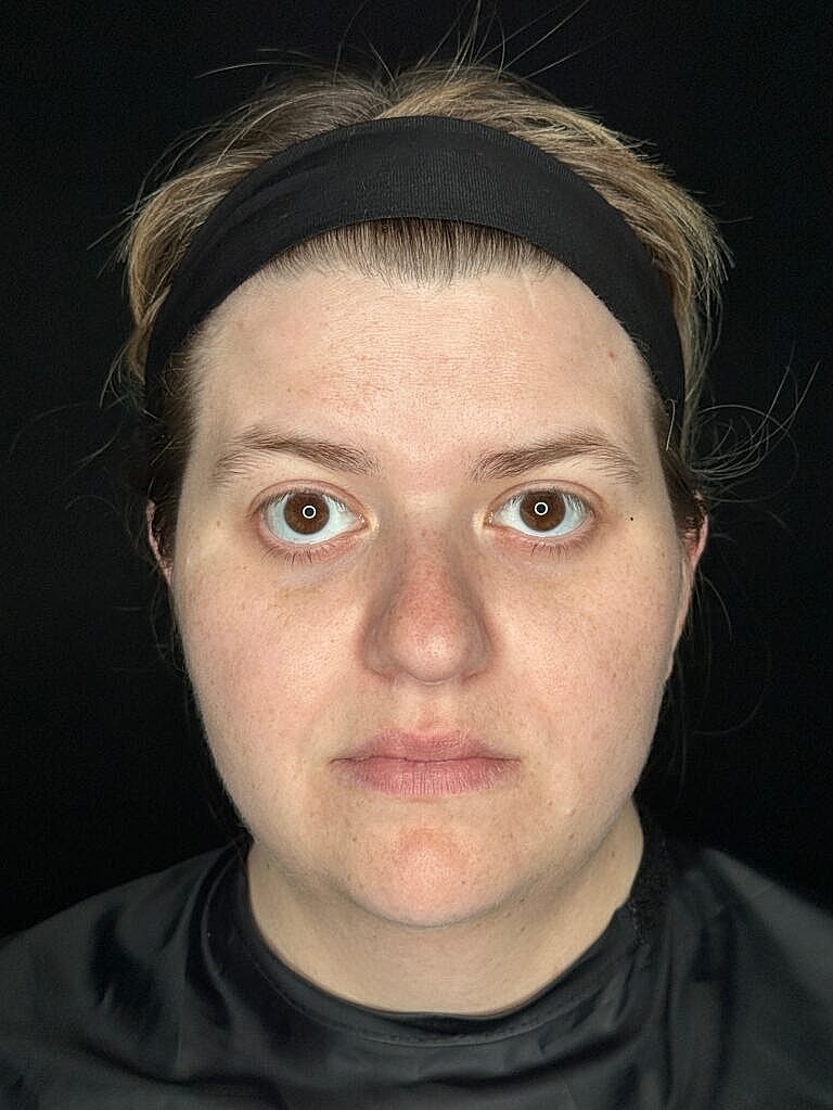 Person with neutral expression against dark background.