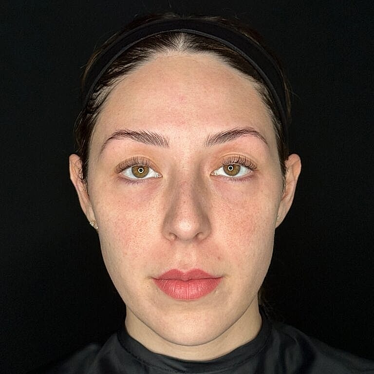 Woman with natural makeup against a black background.