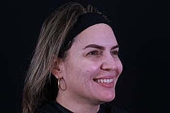 Woman smiling against a dark background.