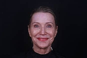 Smiling woman with bright lipstick against black background.