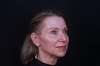 Elderly woman with a serene expression against black background.