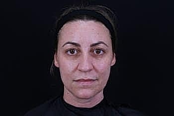 Woman with neutral expression against black background.