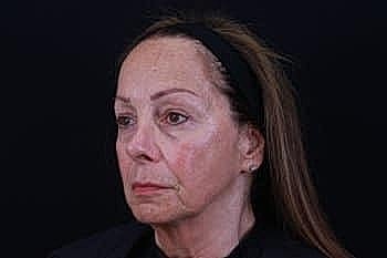 Woman with long hair against dark background.