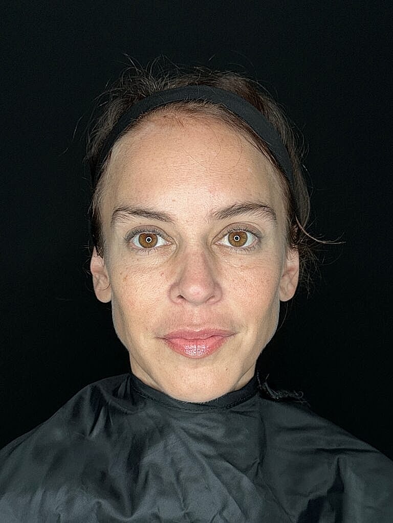 Woman with neutral expression and dark background.
