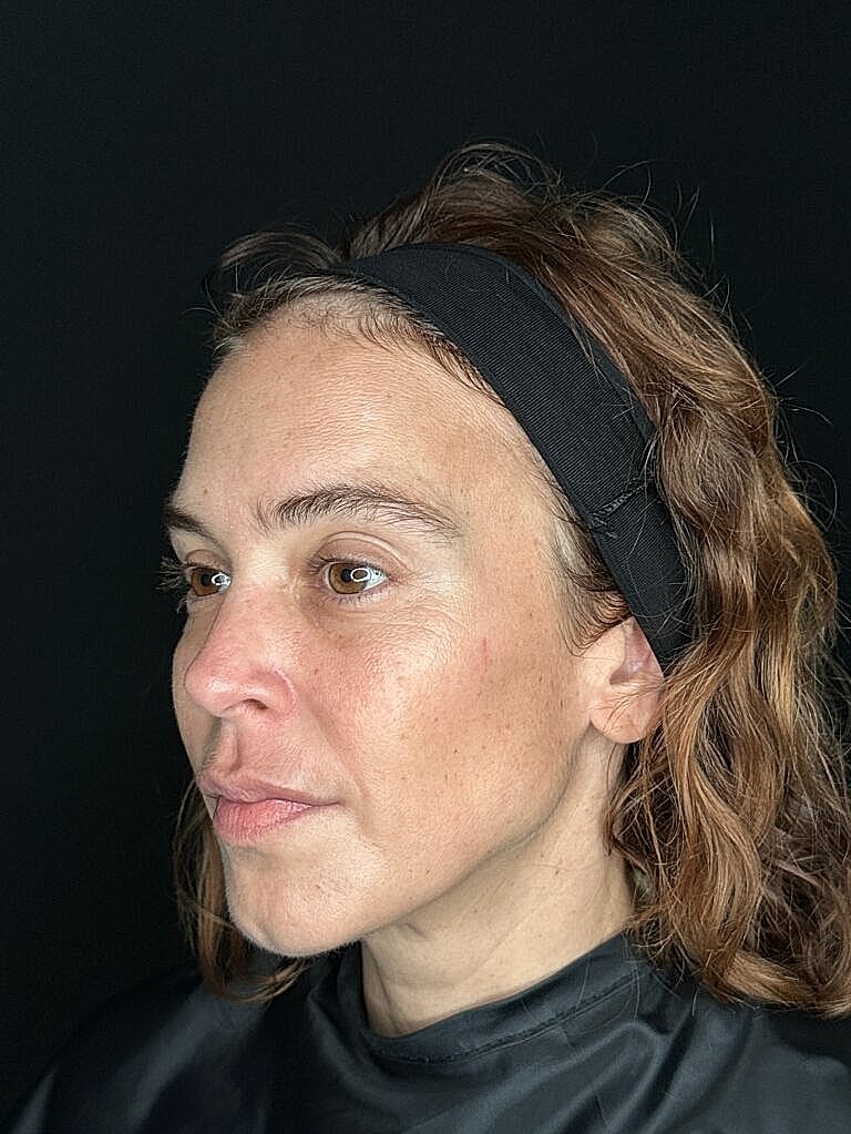 Woman with headband, neutral expression, dark background.