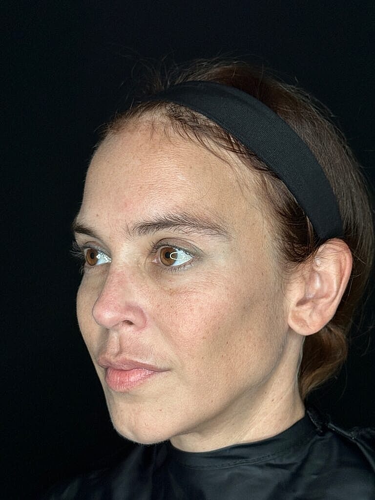 Woman with headband against black background.