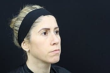 Woman with headband against dark background.