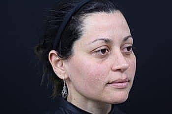 Woman with earrings against a dark background.