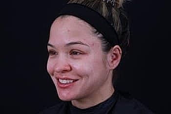Smiling woman with natural makeup against black background.