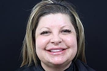 Smiling woman with long hair against black background