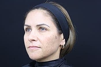 Woman with a headband against a dark background.