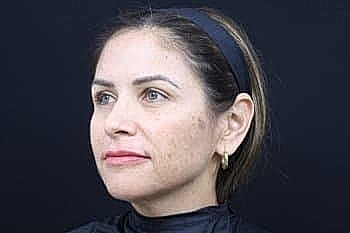 Woman with natural makeup against a black background.
