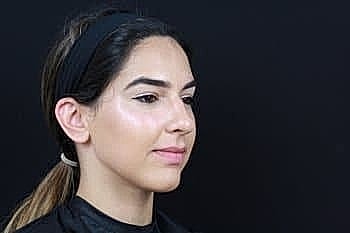 Woman with sleek hair against black background.