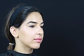 Woman with makeup in profile against black background.