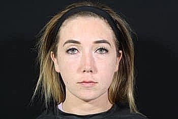 Individual with straight hair against a dark background.