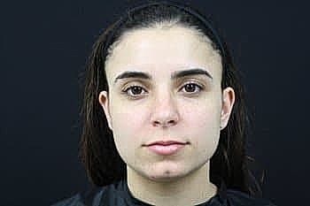 Person with dark hair against black background.