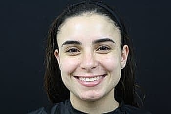 Smiling woman with dark hair and black backdrop.