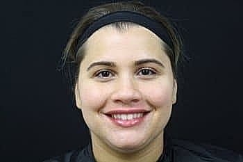 Smiling woman with headband against black background.