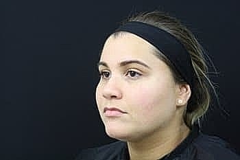 Young woman with headband against dark background.