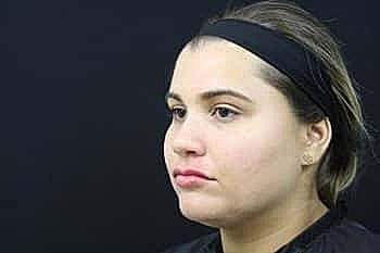 Woman with a headband against a black background.