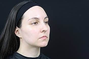 Person with long hair against dark background.