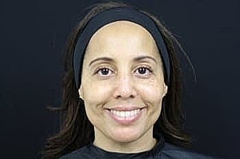 Smiling woman with a headband against a dark background.