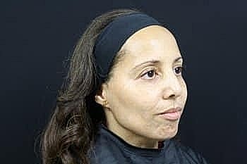 Woman with long hair, profile against black background.