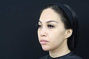 Woman with headband against dark background.