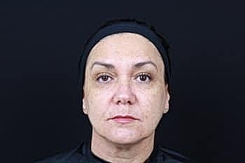 Woman with headband against black background.