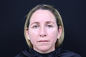 Woman with light hair against dark background.