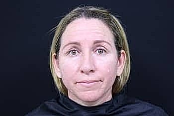 Woman with neutral expression against black background.