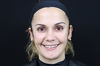 Smiling woman with natural makeup against black background.